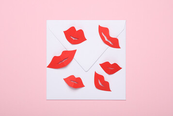 White envelope with red woman's lips cut out of paper on pink background. Love letter. Valentine's Day. Top view