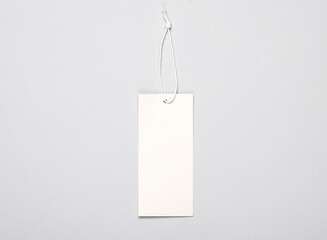 White blank clothing price tag or label mockup with string on gray background. Sale, shopping...