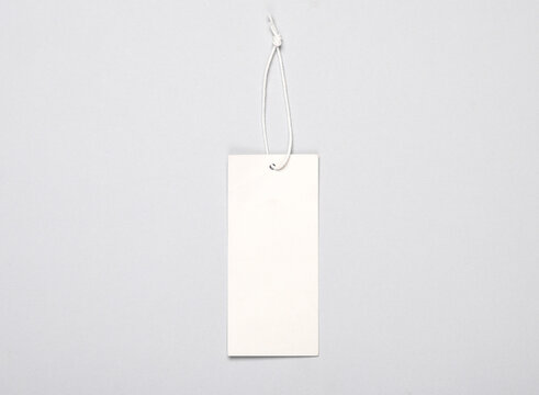 White blank clothing price tag or label mockup with string on gray background. Sale, shopping concept. Top view