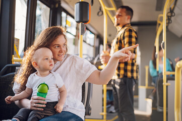 Happy mother and son riding in bus while baby sits in her lap.