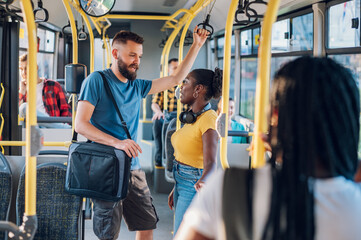 Multiracial friends talking and using a smartphone while riding a bus in the city