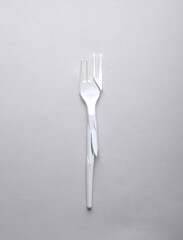 Broken plastic fork on a gray background. Stop plastic pollution, recycling, eco concept