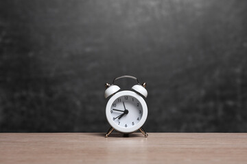 Alarm clock on table against background of chalk board. back to school
