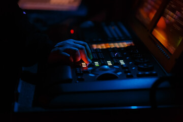 Stage lighting technician working on concert. Professional lights engineer using lights controller desk on music festival