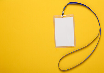 Empty white ID card badge mockup with blue belt on yellow background. Staff identity name tag. Space for text and design. Top view. Flat lay