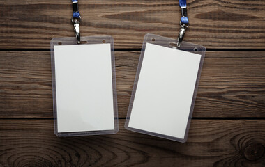 White ID card badges with belt on wooden table. Mockup for design template. Top view