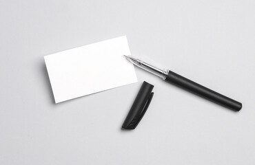 White business card with a pen on a gray background