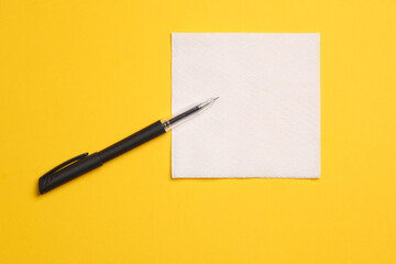 White empty napkin and pen on  yellow background