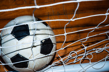 Old soccer ball into a goal net.