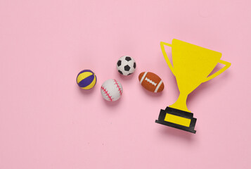 Paper-cut golden winner trophy cup with balls on pink background. Competition, sport, prize, award...