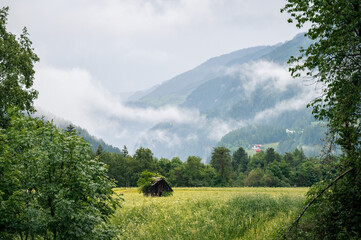 landscape in the mountains with a little house on the field