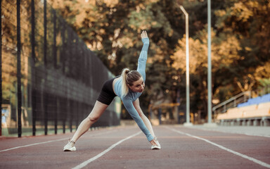Athletic woman doing warm-up before training at the stadium. Healthy lifestyle
