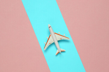 Toy passenger plane on a pink background with a blue stripe. Voyage, Travel concept. Top view