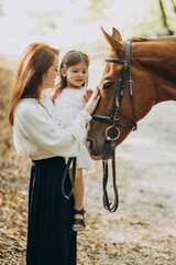 Mother with daughter and horse in forest