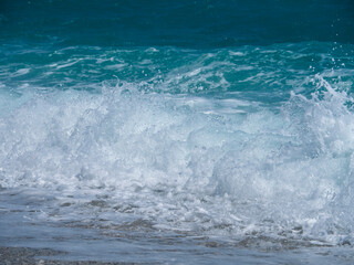 Fototapeta na wymiar Beautiful foam waves on a sunny day in the Aegean Sea on the island in Greece
