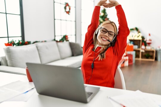 Young caucasian woman call center agent teleworking sitting by christmas tree at home