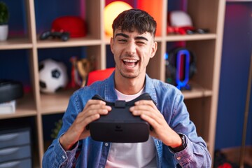 Young hispanic man wearing virtual reality glasses winking looking at the camera with sexy...