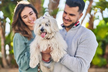 Man and woman holding dog standing together at park