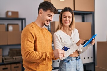 Young man and woman ecommerce business workers using touchpad and credit card at office