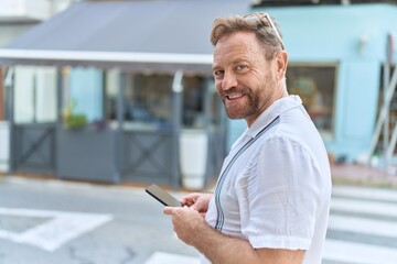 Middle age man smiling confident using smartphone at coffee shop terrace