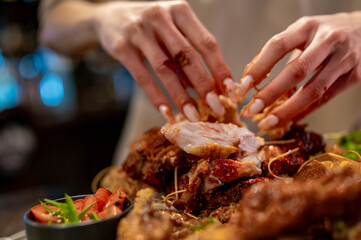 hungry woman hand holding and eatting fried chicken meat in pub