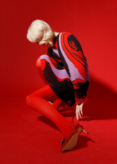 fashion blonde woman model in red dress and red tights posing isolated on scarlet background