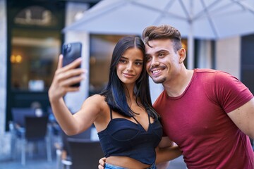 Man and woman couple smiling confident make selfie by smartphone at coffee shop terrace