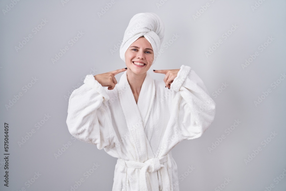 Poster Blonde caucasian woman wearing bathrobe smiling cheerful showing and pointing with fingers teeth and mouth. dental health concept.