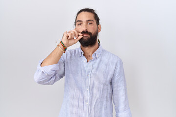 Hispanic man with beard wearing casual shirt mouth and lips shut as zip with fingers. secret and silent, taboo talking