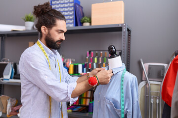 Young hispanic man tailor standing by manikin working at atelier