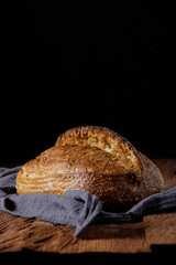 Rustic sourdough wheat bread on a wooden table and dark background. Photo front.