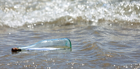 beached bottle with secret message inside and waves