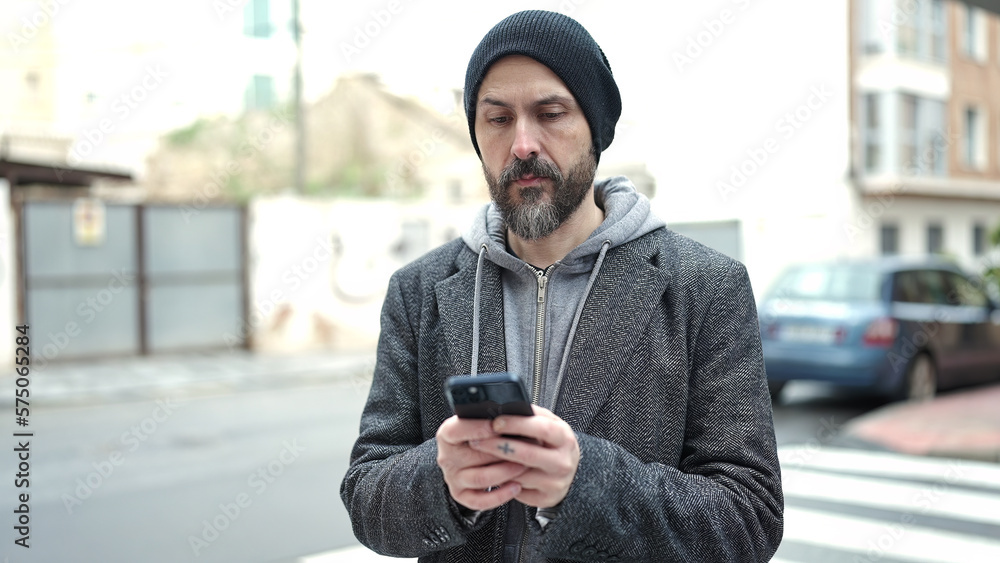 Sticker Young bald man using smartphone with serious expression at street