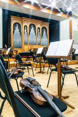 stringed musical instruments of the symphony orchestra lie on the stage before the concert rehearsal. Violins cellos double basses on an empty stage