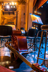 stringed musical instruments of the symphony orchestra lie on the stage before the concert rehearsal. Violins cellos double basses on an empty stage