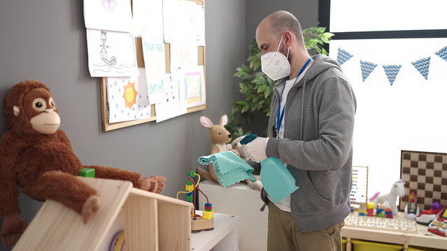 Young Bald Man Preschool Teacher Wearing Medical Mask Cleaning At Kindergarten