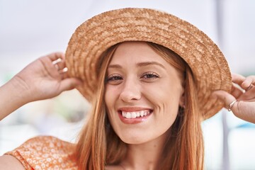 Young redhead woman tourist smiling confident wearing summer hat at street