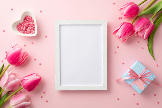 8-march concept. Top view photo of photo frame pink tulips heart shaped saucer with sprinkles and small blue giftbox on isolated pastel pink background with blank space