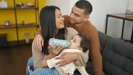 Couple and son drinking milk by feeding bottle at home