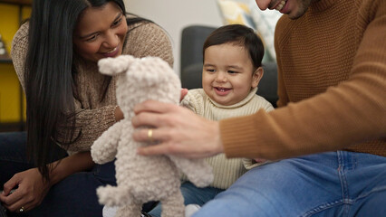 Couple and son playing with teddy bear sitting on floor at home