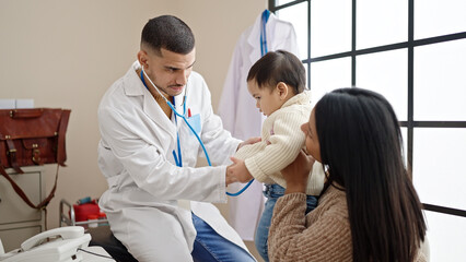 Obraz premium Couple and son examining baby with stethoscope at clinic