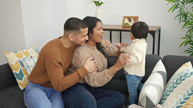 Couple and son hugging each other sitting on sofa at home