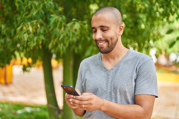 Young latin man smiling confident using smartphone at park