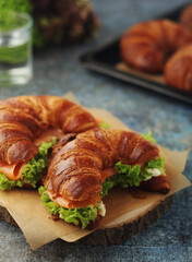Freshly baked croissants with salmon and salad on the table