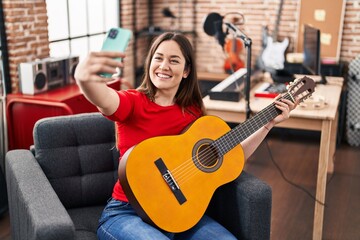 Young woman musician make selfie by smartphone playing classical guitar at music studio