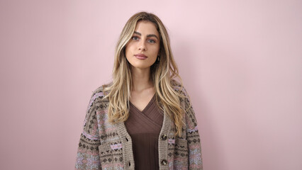 Young blonde woman looking to the camera with relaxed expression over isolated pink background