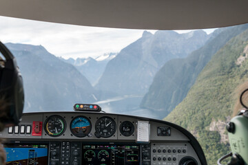 Cockpit in einem Kleinflugzeug in den Bergen mit Gipfeln und Seen.