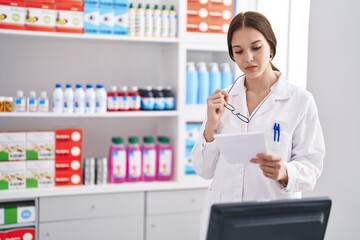 Young woman pharmacist reading prescription at pharmacy