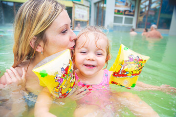 Young mother and daughter in the swimming pool in aquapark. Leisure activity.