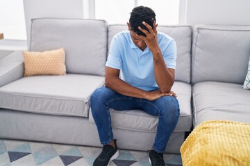 Young latin man stressed sitting on sofa at home
